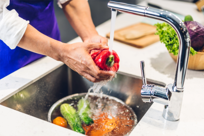 resh vegetables being rinsed at a kitchen sink, showing the benefits of professional water treatment in Ohio.