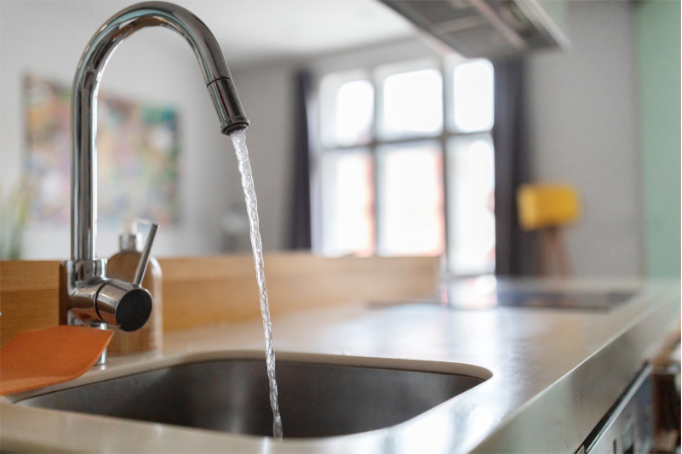 Clean water flowing from a modern kitchen faucet after installation of a whole house backwashing carbon filter.