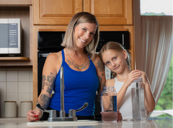 Ohio mom and daughter at a kitchen sink filling water bottles, showcasing a trusted hard water solution that improves home water quality for families in Columbus, Dayton, and Cincinnati.