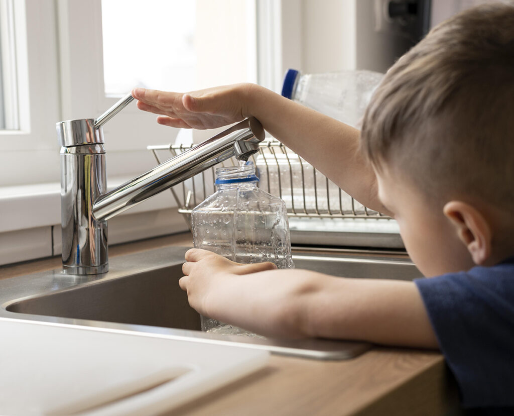 Kid filling bottle with tap water