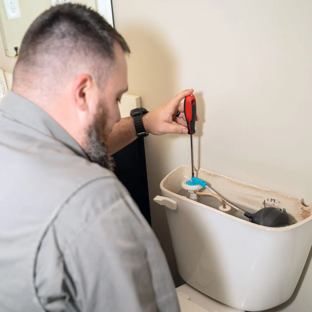 technician servicing bathroom toilet